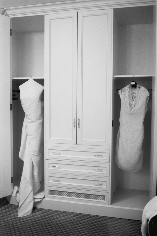 photo by New York City based wedding photographer Karen Hill - black and white photo of wedding dress and short reception dress hanging in closet